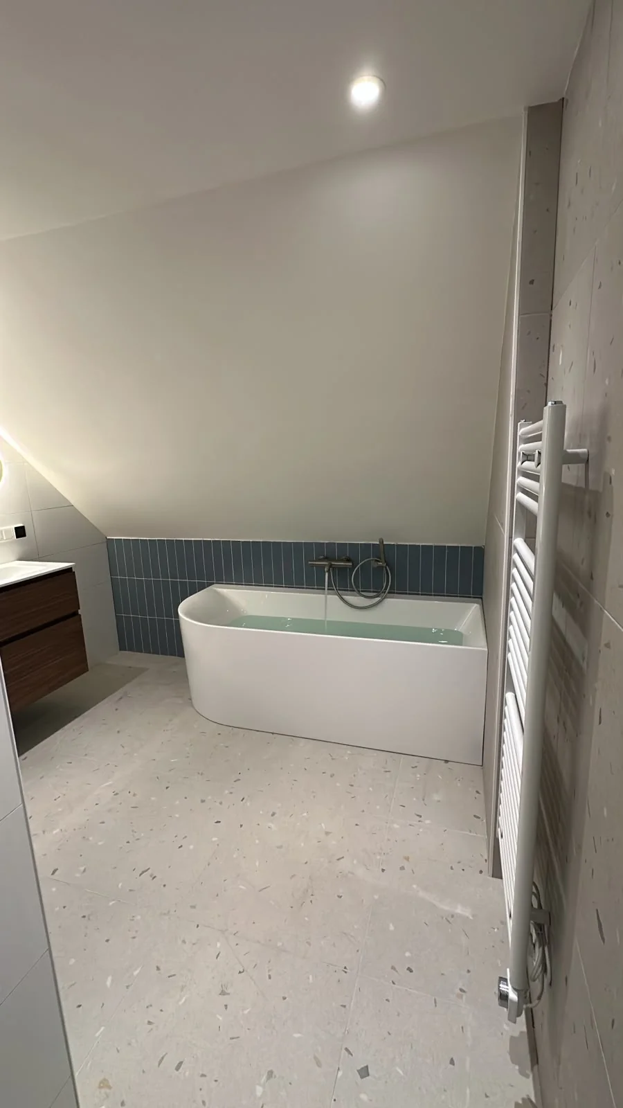 Back-to-wall ligbad met blauwe accenttegels in badkamer onder schuin dak Utrecht