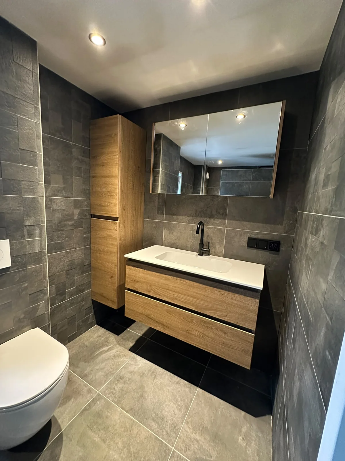 Zwevend houtlook wastafelmeubel met spiegelkast in de gerenoveerde badkamer